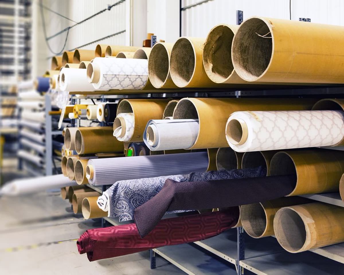 Rolls of woven and knitted fabric stacked in a textile warehouse